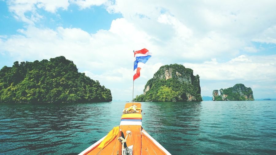 Looking over the bow of a longtail boat towards wooded limestone islands