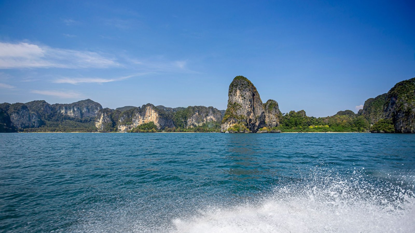 The Railay peninsula's limestone cliffs seen from a boat, with wake in the foreground