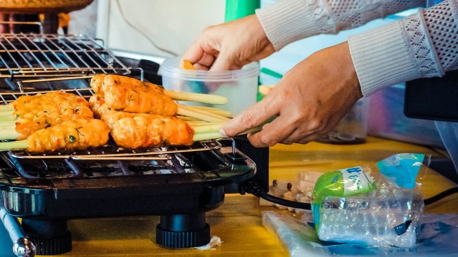 Des brochettes qui grillent sur un stand de cuisine de rue