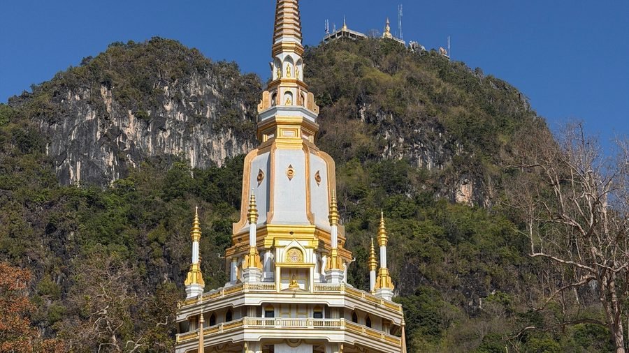 Le grand chedi blanc et or du Wat Tham Suea (temple du Tigre) au pied de sa falaise, les sanctuaires du sommet visibles en haut